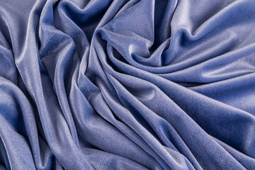 many compressed folds of velvet fabric of blue or ink color. Abstract festive fabric background.