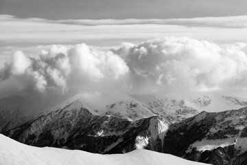 Obraz premium Black and white snowy mountains in clouds and off-piste slope