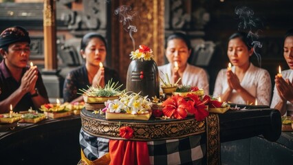 Balinese people praying with offerings and candles at a temple in bali, indonesia.