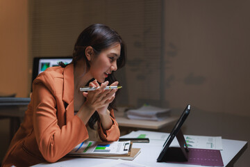Young businesswoman having virtual meeting on tablet at night