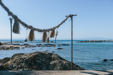 海辺に張られたしめ縄と青い海、日本の信仰を感じる風景