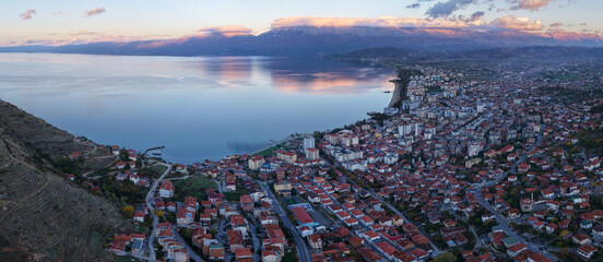 Aerial blue hour panorama of Pogradec, Albania, stretching along the calm shoreline of Lake Ohrid with soft mountain reflections.