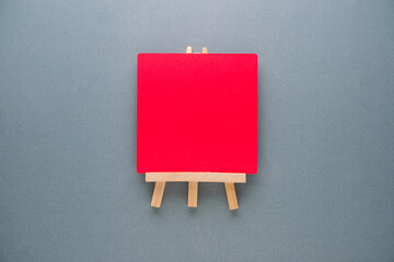 Blank red plate on a small easel, representing creative space and artistic activity