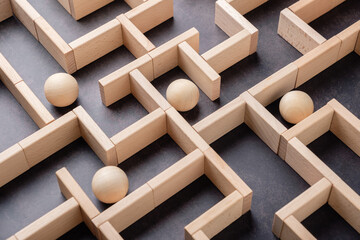 Wooden maze with multiple balls, organizations navigating complex systems, strategic planning, business challenges, people facing different choices, decisions, and direction
