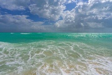 Turquoise water wave motion. Summer beach. Calm beach. Luxury seaside resort. Bright sky and waves on the beach. Beautiful foamy shoreline. Sea background. Blue ocean. Sandy beach.