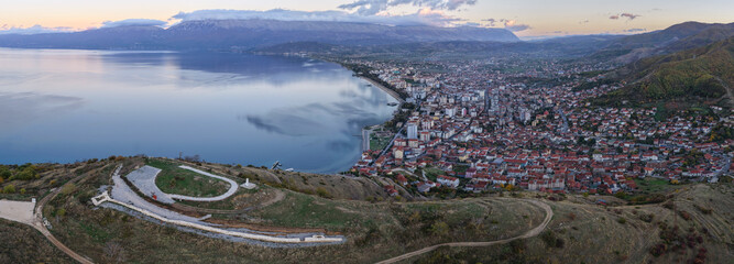 Panoramic blue hour aerial view of Pogradec, Albania, overlooking Lake Ohrid, the city shoreline, and surrounding hills.