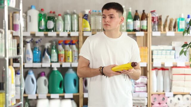 Male shopper carefully selects a cleaning product for washing parquet and laminate floors in a supermarket. High quality 4k footage