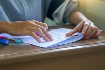 High school or university students sitting in a classroom, focused on writing their answers on examination papers during a final test or assessment.