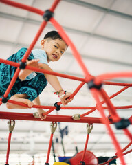 Asian Little Boy Climbing Rope Playground, Active Child Playing and Developing Skills