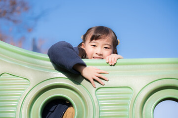 Children playing on playground equipment in a park under blue skies Images of children's outings and leisure activities	