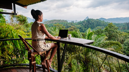 Fototapeta premium Working from a serene balcony overlooking the lush green landscape of Khao Sok in Thailand