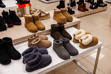 A variety of suede winter slippers and ankle boots in earthy shades with plush lining are neatly arranged on a store display. No visible logos or trademarks © ugis
