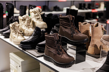 A variety of winter boots, including brown, black, beige, and tan models, are neatly arranged on a...