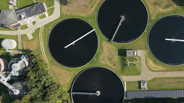 Top-down drone shot of circular wastewater treatment basins forming geometric patterns in an industrial environmental facility.
