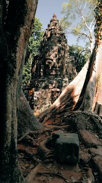 Vertical slow rightward slide reveals the ancient stone entrance and surrounding jungle vegetation at Victory Gate in Angkor Thom