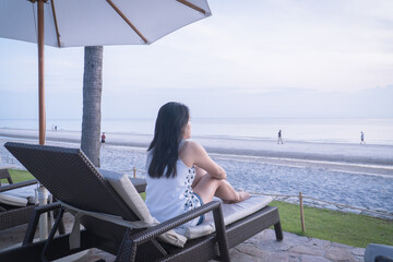 Asian woman relaxing on beach chair enjoying beautiful seaside view during summer vacation