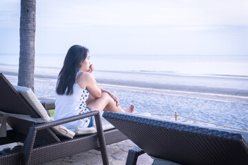 Asian woman relaxing on beach chair enjoying beautiful seaside view during summer vacation