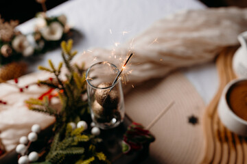 Moody holiday still life with glass, greenery and soft candlelight. Cozy winter atmosphere and calm festive mood.
