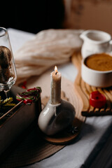 Minimal winter still life with candle, coffee cup and festive decor. Calm cozy mood and warm Christmas atmosphere.