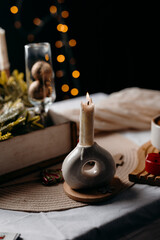 Minimal festive still life with candle and warm bokeh lights. Calm Christmas mood and cozy winter interior styling.