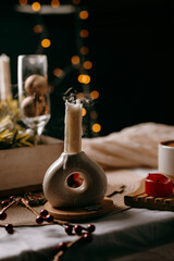 Minimal winter still life with candle, ceramic decor and soft festive lights. Cozy Christmas atmosphere and calm seasonal mood.
