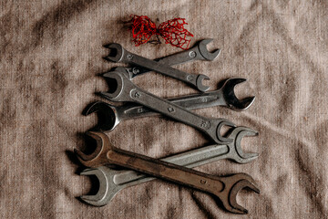Creative Christmas tree made from metal wrenches on linen background. Conceptual holiday still life and industrial festive art.