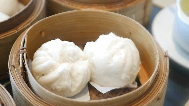 close up view to a steamer full with chinese bun dimsum in hongkong style with hot streaming ready to eat in panning view,chinese dimsum food eating