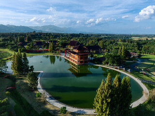 Fototapeta premium Aerial of Japanese-style lake resort surrounded by fields and hills