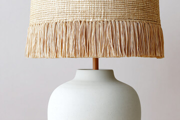 Horizontal shot of modern table lamp with matte ceramic base and natural woven elements (rattan, wicker, jute), soft diffused daylight, minimal beige interior, shallow depth highlighting texture.