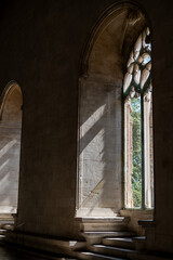 Sun rays streaming through ancient gothic window in a stone cathedral interior