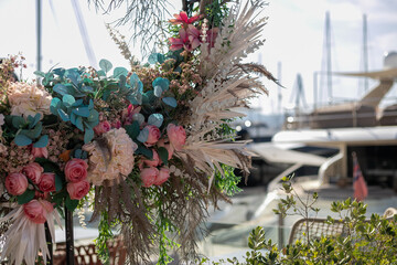 Luxury floral wedding decoration at a yacht marina with roses and pampas grass
