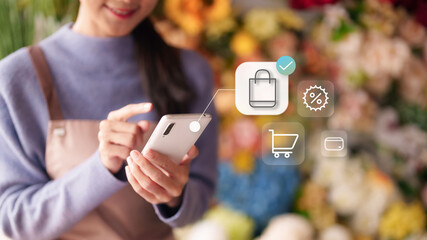 Asian woman small business owner flower shop mobile phone digital commerce online order processing secure payments retail technology entrepreneur managing store