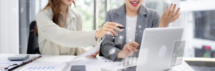 Asian adult businesswomen analyze market data together in modern office using laptop computer for project management and strategic planning
