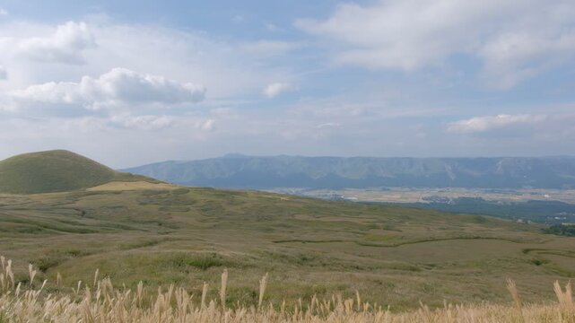Komezuka volcano in Aso, Kumamoto, Kyushu, Japan, green grass field cover the mountain with blue sky and cloud background