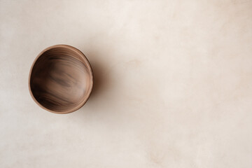 Empty wooden bowl against neutral light brown background. Suitable for food blog, kitchen decor, mindfulness concept, natural products advertisement.