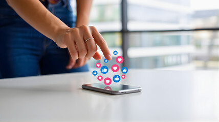 Social media engagement with likes, hearts, and thumbs up icons appearing above a smartphone held by a person