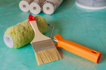 Wallpaper, roller, and brush ready for apartment renovation. Tools for room renovation. Apartment renovation concept.