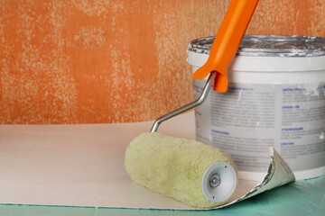 Paint, roller, and brush ready for an apartment renovation. Tools for the room renovation are displayed against an old wall. Apartment renovation concept