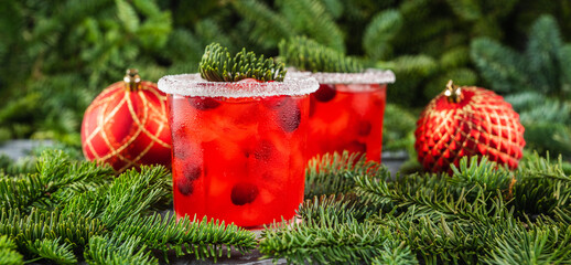 Red christmas cocktail with cranberry juice on the fir branches background. Christmas mood. Selective focus.
