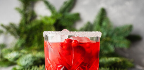 Red christmas cocktail with cranberry juice on the fir branches background. Christmas mood. Selective focus.