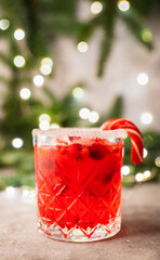 Red christmas cocktail with cranberry juice on the fir branches background. Christmas mood. Selective focus.