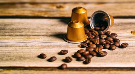 Coffee capsules and beans on wooden table, closeup