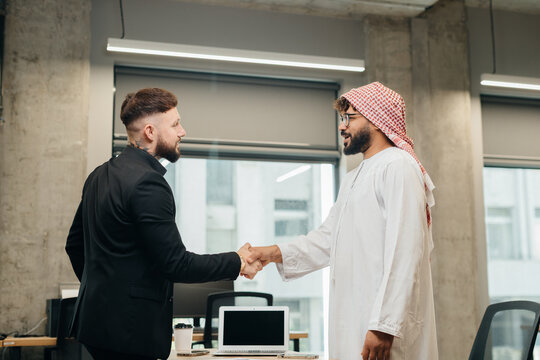 Diverse businessmen shaking hands closing successful deal in office