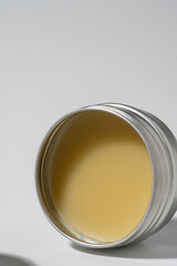Close-up of natural yellow balm in open round metal tin.