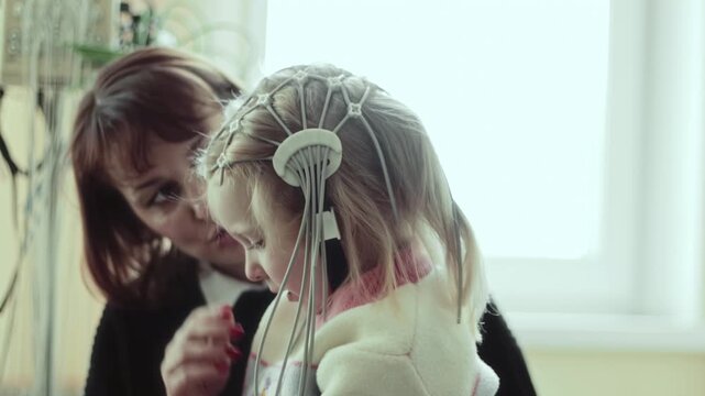Electroencephalography, medical professional carefully applies EEG net on head of Caucasian girl patient in clinical setting, procedure for brain electrical activity measurement