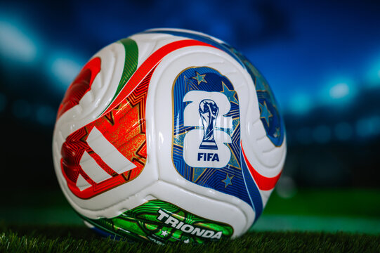 FIFA World Cup 2026 official football resting on green turf with a blurred stadium backdrop and event branding Official Trionda ball on green Grass