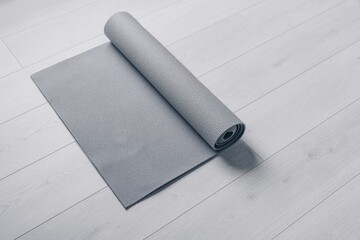 A Rolled-Up Exercise Mat Laid Out on a Light Wooden Floor: Perfect for Yoga, Pilates, and Fitness Activities in a Modern Home Setting