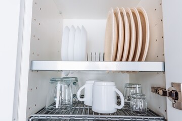 Organized Kitchen Cabinet with Neatly Stacked Dishes, Glassware, and Utensils Displaying a Minimalistic and Functional Design for Efficient Cooking and Dining