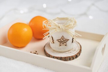 Cozy winter still life with oranges and handmade candle holder on a wooden tray