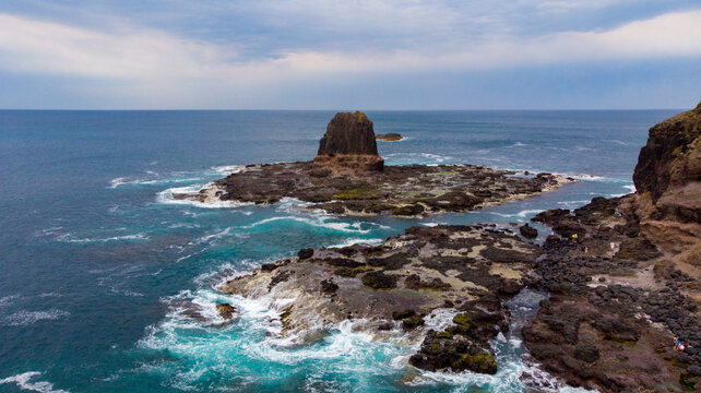 Aerial view of Pulpit Rock standing defiant against the crashing waves, a sentinel of time and tide, Cape Schanck, Victoria, Australia.